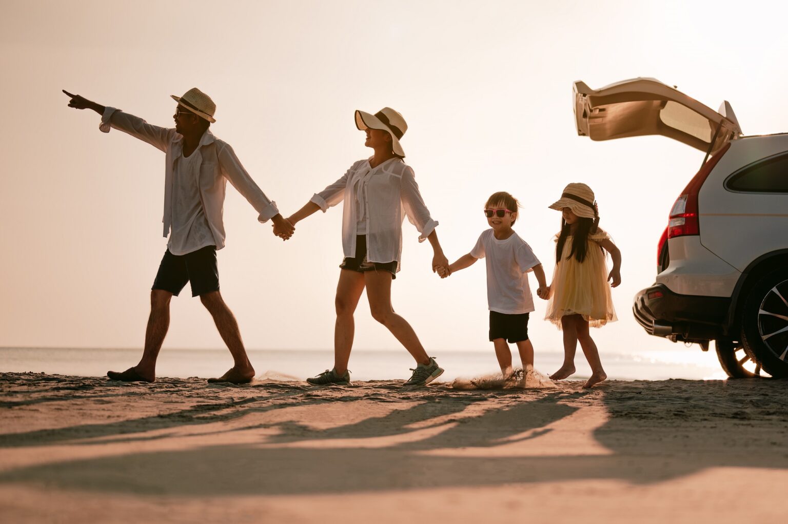 Asian family on the beach.Vacation time. Happy father, mother and son enjoying road trip the summer holidays.Parents and children are sitting on a hatchback with a sea background.